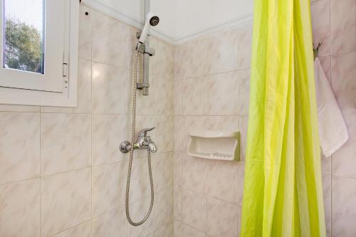 a shower with a yellow shower curtain in a bathroom at Areti Orfeas Apartment 7 in Vasilikos