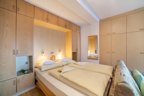 a bedroom with a large bed and wooden cabinets at Residence Pichler Apartment 7 in San Leonardo in Passiria