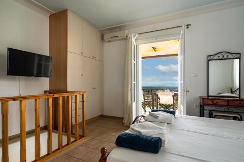a room with a bed and a tv and a balcony at Afroksilia Villa Gardenia in Lefkada