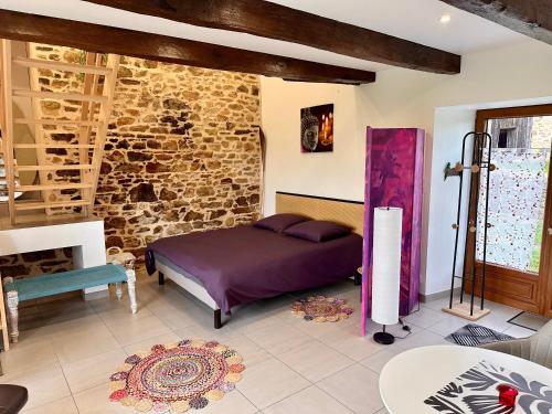 a bedroom with a bed and a stone wall at Gite Cosy Forme et Bien-etre in Masseret