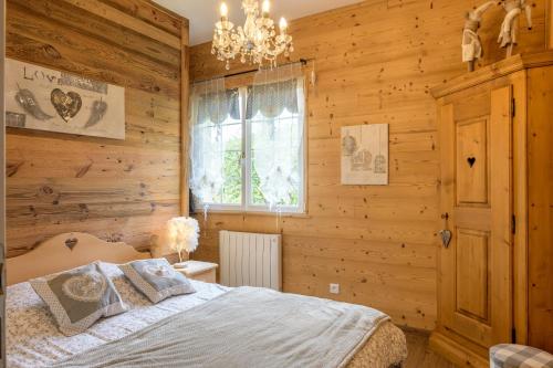 a bedroom with a bed and a chandelier at La Petite Chaumière avec sauna in Saint-Maurice-sur-Moselle