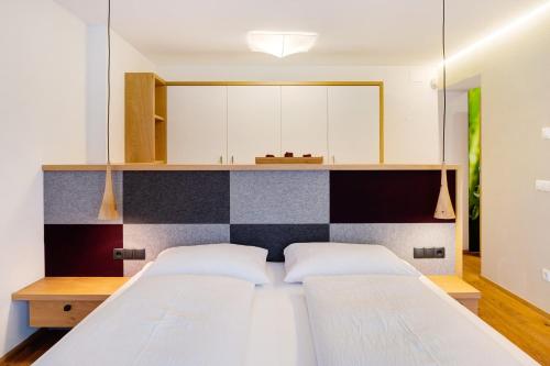 a bedroom with a bed with a black and white headboard at Angerle Alm Apt Alpenglühen in Carezza al Lago