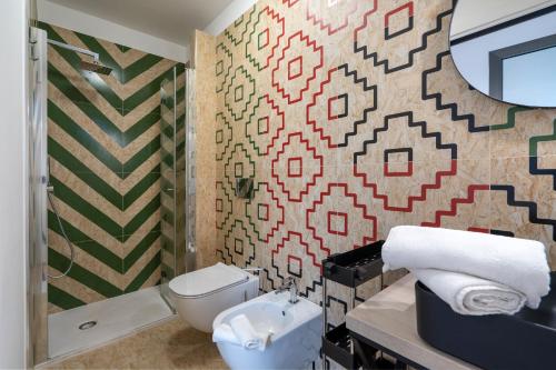 a bathroom with a toilet and a mosaic wall at La Casa di Laura in Putignano