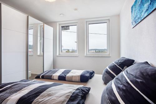 two beds in a room with windows at Ferienwohnung am Kappenturm in Hayingen