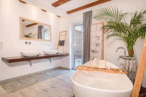 a bathroom with two sinks and a tub and a plant at Ferienwohnung Relax in Sigmarszell
