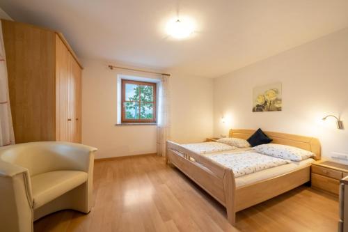a bedroom with two beds and a chair at Stettnerhof Wohnung Ifinger in Vollan