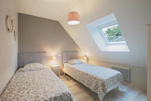 two beds in a bedroom with a roof at Gîte La Clémençaie in Réminiac