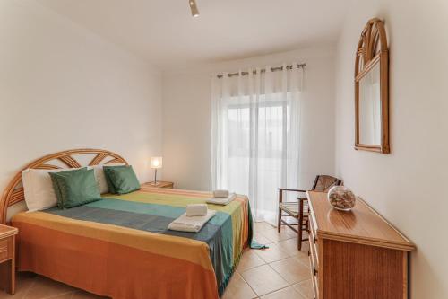 a bedroom with a bed and a table and a window at Sail Away in Quarteira