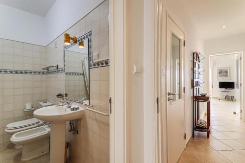 a white bathroom with a sink and a toilet at Sail Away in Quarteira