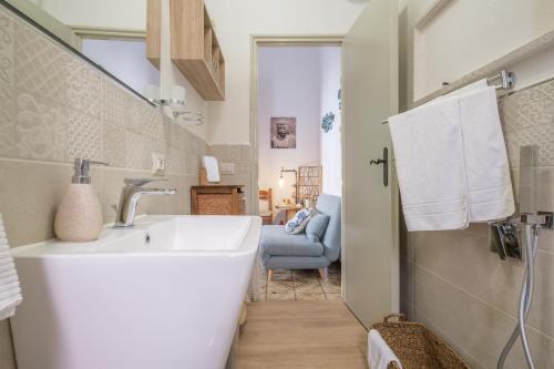 a white bathroom with a sink and a chair at Tyndaris home in Oliveri