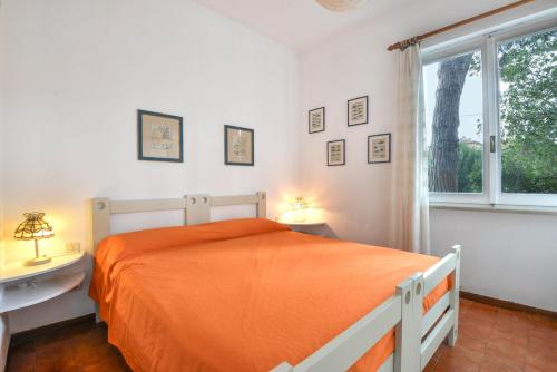 a bedroom with an orange bed and a window at Villetta Serena in Procchio