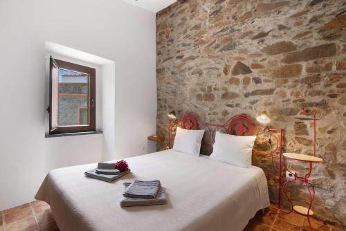 a bedroom with a large white bed with a stone wall at Recanto d'Aldeia in Alcoutim