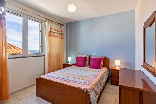 a bedroom with a bed with pink pillows and a window at Sonho Dourado Apartamento de praia in Porto Santo