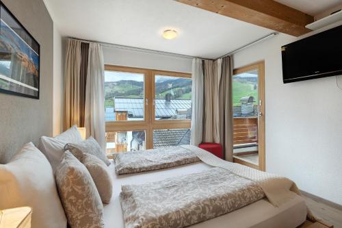 a bedroom with two beds and a large window at Ciasa Irene Dreizimmerwohnung in La Villa