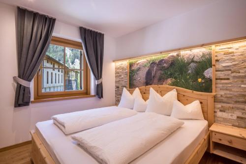 a bedroom with a white bed with a painting on the wall at Lechnerhof Murmeltier in Valles