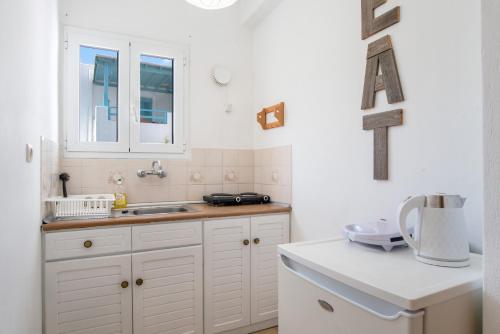 a kitchen with white cabinets and a sink at Livadia Seaside Studios 10 in Parikia