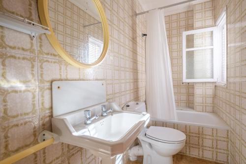 a bathroom with a sink and a toilet and a mirror at Apartamento las Palmeras 2 in Benicarló