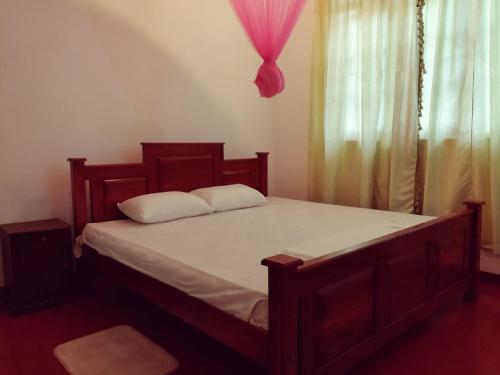 um quarto com uma cama de madeira com lençóis brancos e uma janela em Sunrise Beach Inn em Ambalangoda