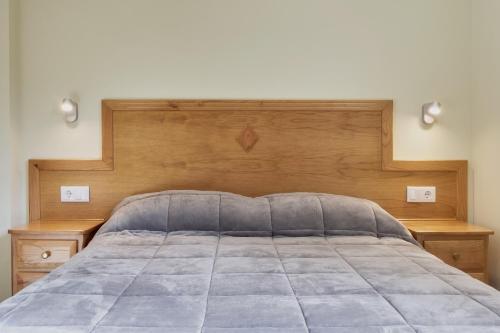 a bed with a wooden headboard and two night stands at Valle del Ibias - Primero Derecha in Cecos