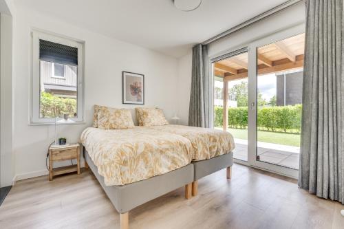 a bedroom with a bed and a large window at Casa Bos Schotsman Wellness in Kamperland