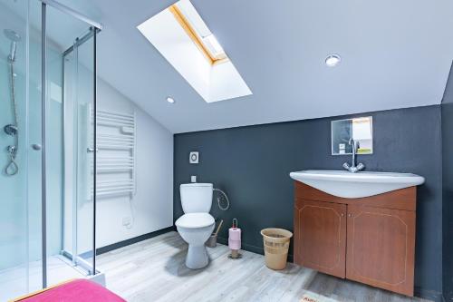 a bathroom with a sink and a toilet and a skylight at La maison dans les noyer in Sainte-Eulalie