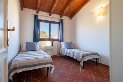 two beds in a room with a window at Villa Giada in Stintino