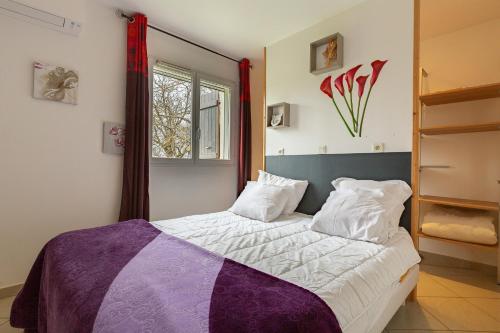 a bedroom with a bed with purple and white sheets at La maison dans les noyer in Sainte-Eulalie