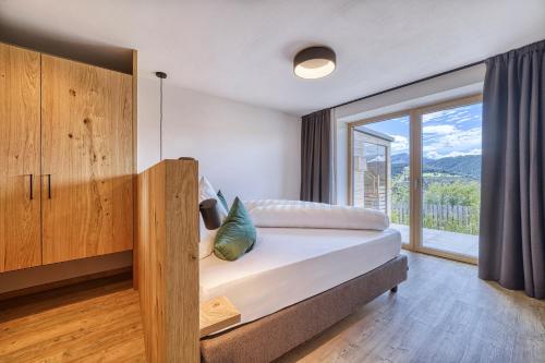a bedroom with a bed and a large window at Chalet Schlossberg Rosengarten in Nova Ponente