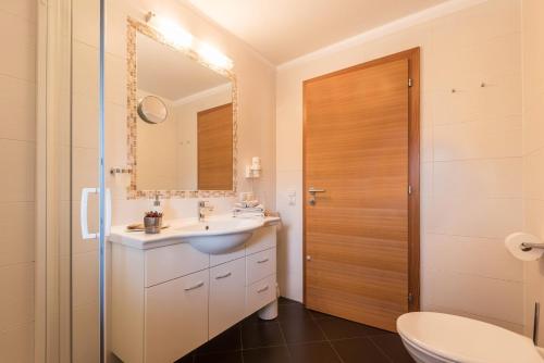 a bathroom with a sink and a mirror and a toilet at Kristiania Apartement Typ A2 in Siusi