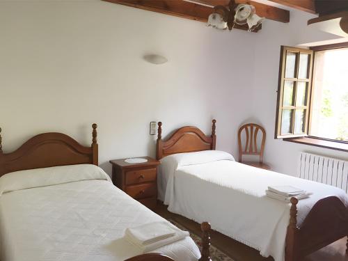 a bedroom with two beds and a window at Posada Rural La Capellanía in Celis