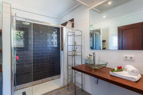 a bathroom with a glass shower and a wooden counter at Es Pujols in Artá