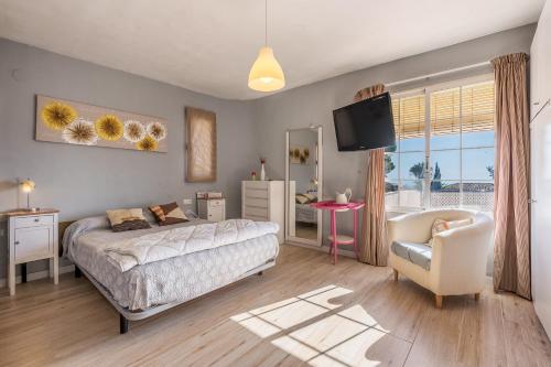 a bedroom with a bed and a chair and a television at Apartamentos Villa Martinez in Salobreña
