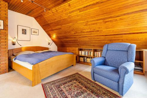 a bedroom with a bed and a blue chair at Ferienhaus Hebborn in Bergisch Gladbach