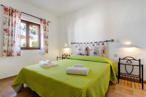 a bedroom with a green bed with two towels on it at Monte do Tanoeiro - Casa da Barrica in Rogil