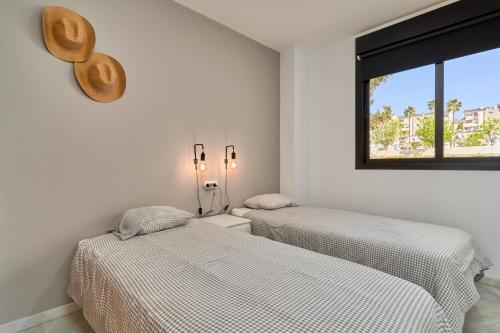 two beds in a white room with a window at 2-bedroom apartment with seaview in Nerja