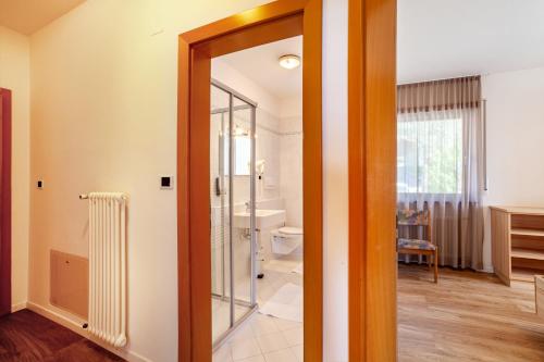 a bathroom with a glass door leading to a toilet at Gartenheim App Leonhard in Schenna