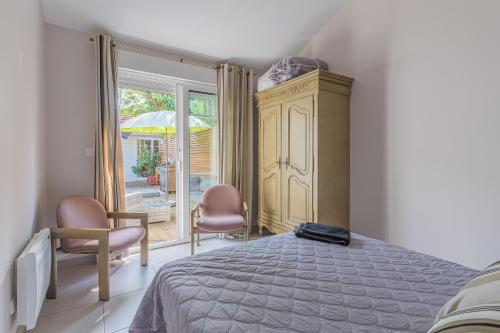 a bedroom with a bed and two chairs and a window at Maison Le Moulleau in Arcachon