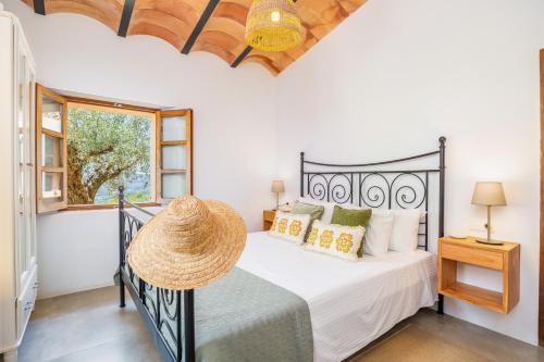 a bedroom with a black bed with a straw hat on it at Els Abats in Fornalutx