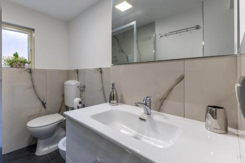 a white bathroom with a sink and a toilet at Dimora D'Incanto in Ragusa
