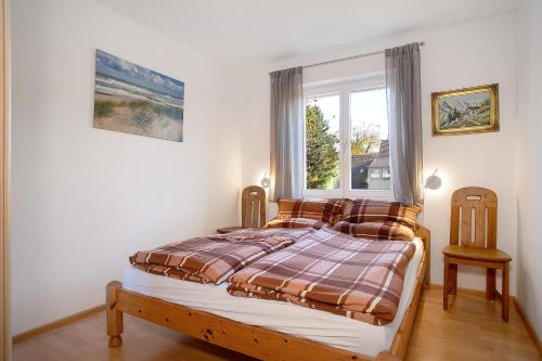 a bedroom with a bed with a plaid blanket and a window at Haus Blaulichtfamilie in Opfenbach