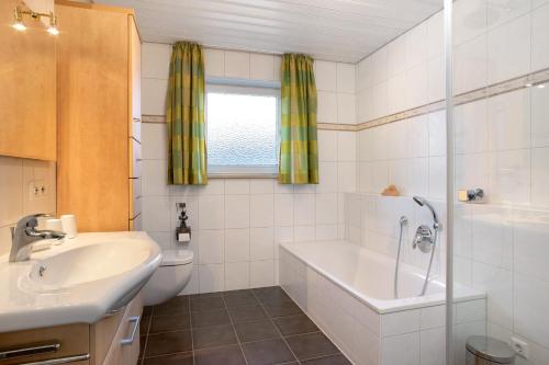 a bathroom with a tub and a sink and a toilet at Haus Blaulichtfamilie in Opfenbach