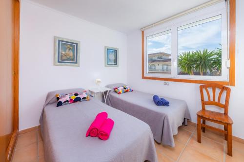 a room with two beds and a chair and a window at Can Bennasar in Can Picafort