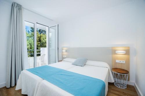 a white bedroom with a bed and a window at Apartament Massanet 1a in Canyamel