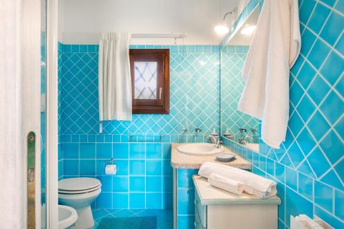 a blue tiled bathroom with a toilet and a sink at Bia de Bados B5 in Olbia