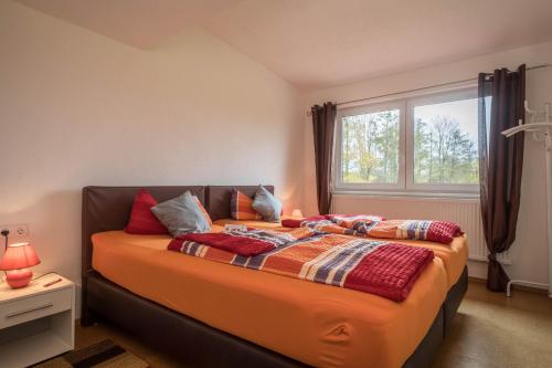 a bedroom with a bed with an orange comforter and a window at Ferienwohnung Steinhilber 1 in Eriskirch