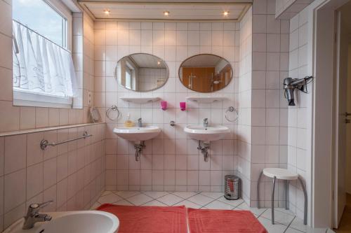a bathroom with two sinks and two mirrors at Ferienwohnung Steinhilber 1 in Eriskirch