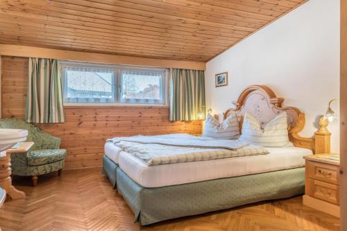a bedroom with a large bed and a chair at Villa Soldanella in Ortisei