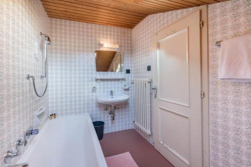 a bathroom with a sink and a shower and a white door at Villa Soldanella in Ortisei