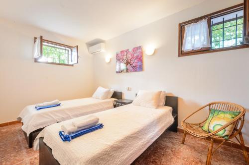 two beds in a room with a chair and windows at Ca Nostra Ibiza in Sant Josep de sa Talaia