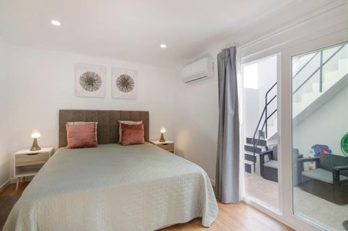 a white bedroom with a bed and a staircase at Telmus Villa Rc D in Monte Gordo